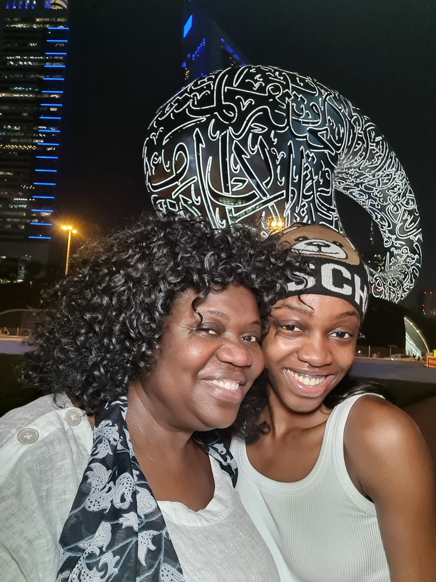 Original photograph of Artist MINA at the Museum of the Future in Dubai city skyline, UAE. Arabic calligraphy details. Personal reference photograph connected to the original painting.