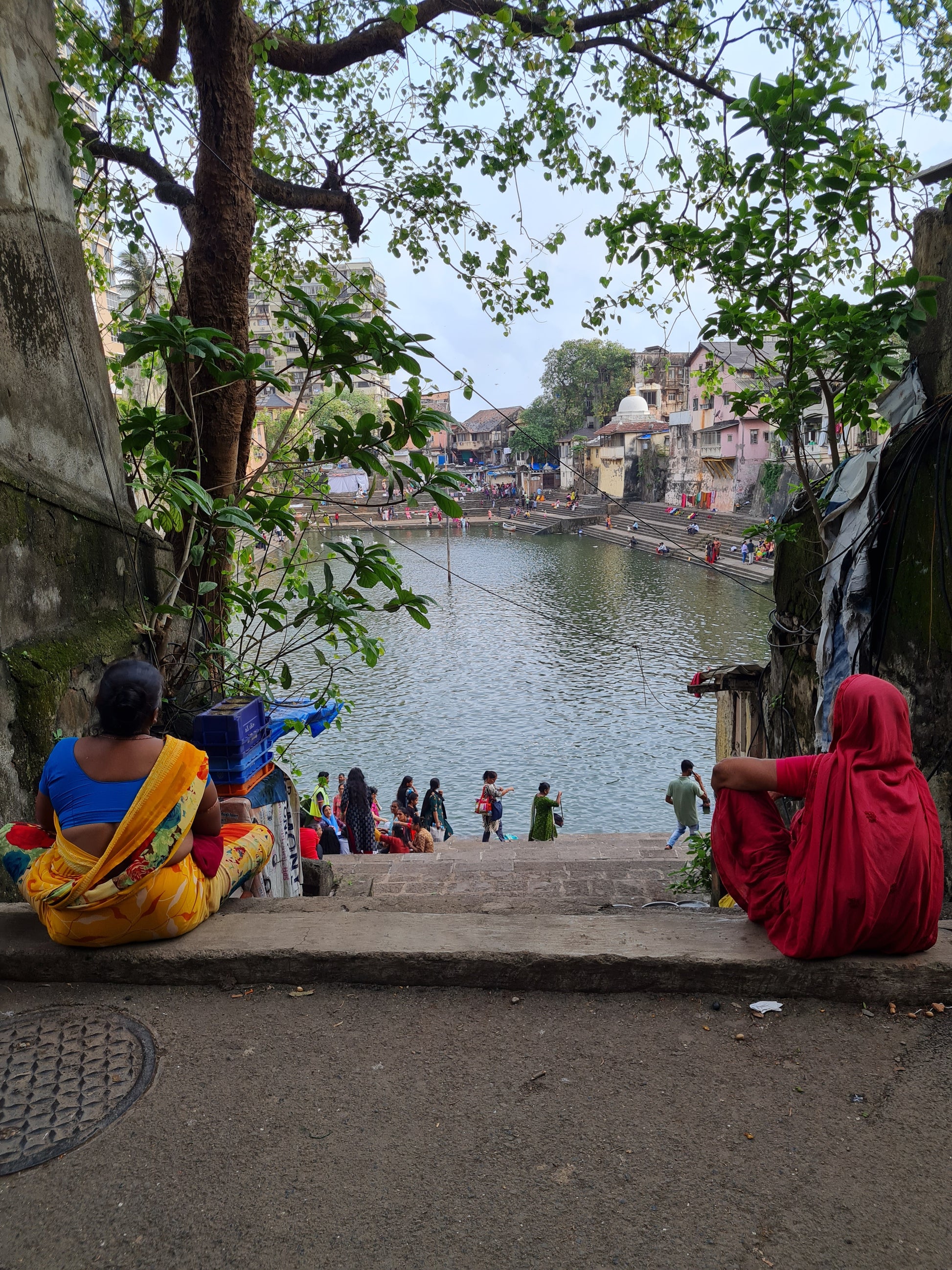 Reference photograph of Banganga Water Tank in Mumbai, showing two women seated near the steps overlooking the water, used as inspiration for MINA’s painting Women at Banganga Water Tank — Mumbai.